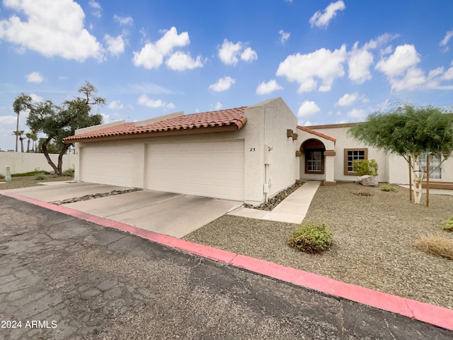 view of front of house with a garage, a tile roof, driveway, and stucco siding