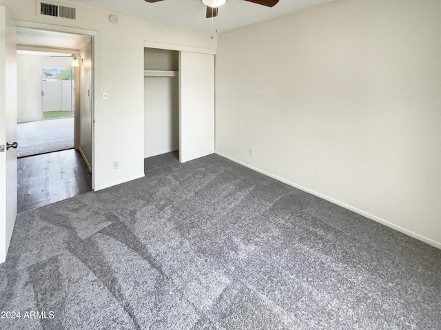 unfurnished bedroom with ceiling fan, visible vents, baseboards, a closet, and dark colored carpet