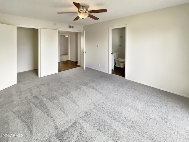 unfurnished bedroom featuring a textured ceiling, carpet floors, visible vents, and ensuite bathroom