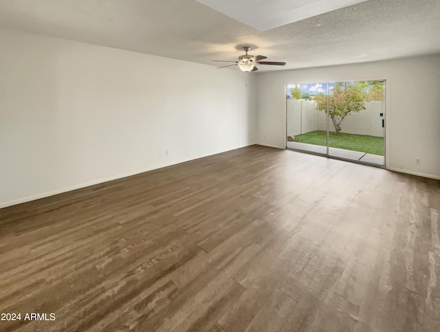 spare room featuring a textured ceiling, dark wood-style flooring, a ceiling fan, and baseboards