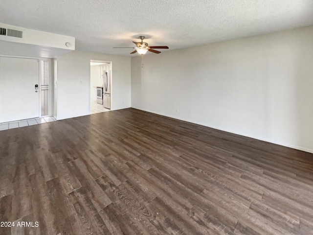 interior space with a textured ceiling, ceiling fan, wood finished floors, and visible vents