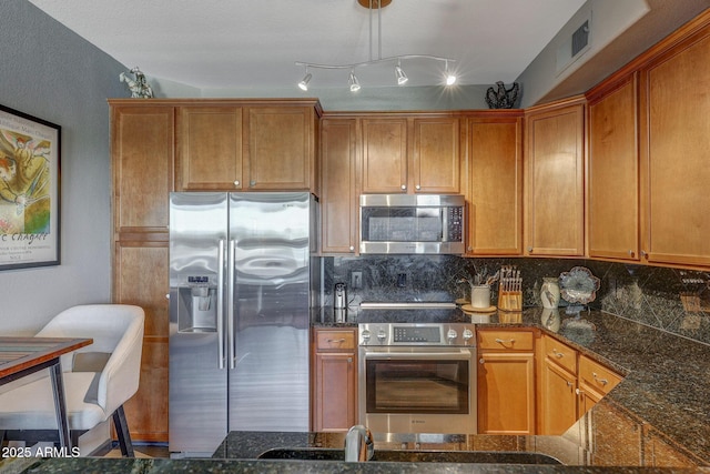 5303 N 7th St Unit 331, Phoenix, AZ 85014 - kitchen featuring stainless steel appliances, backsplash, dark stone counters, and brown cabinets
