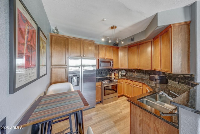 5303 N 7th St Unit 331, Phoenix, AZ 85014 - kitchen with stainless steel appliances, tasteful backsplash, light wood-style floors, dark stone counters, and brown cabinets