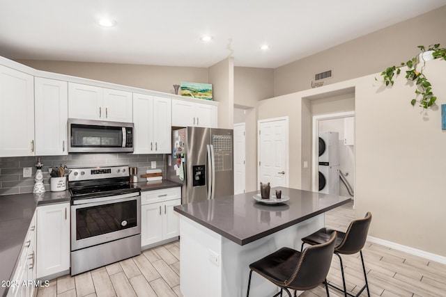 1583 N Constellation Ct, Gilbert, AZ 85234 - kitchen featuring stainless steel appliances, stacked washer / drying machine, dark countertops, wood tiled floors, and backsplash