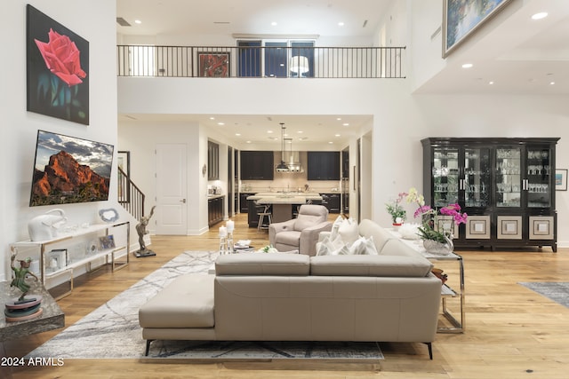 living room with light hardwood / wood-style flooring and a towering ceiling