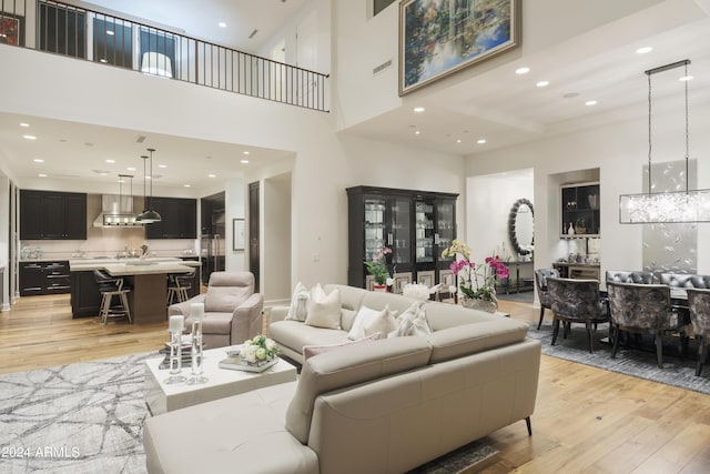 living room with light hardwood / wood-style floors and a towering ceiling