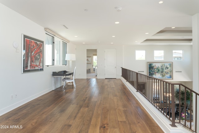 hallway with a tray ceiling and dark hardwood / wood-style floors