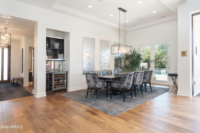 dining space with wine cooler, wood-type flooring, and a raised ceiling