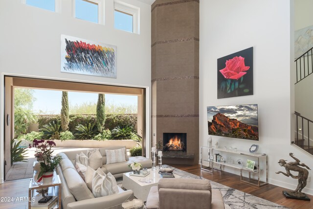 living room featuring dark hardwood / wood-style flooring, a high ceiling, and a tiled fireplace