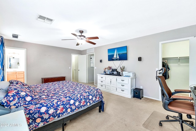 carpeted bedroom featuring a spacious closet, ceiling fan, ensuite bath, and a closet