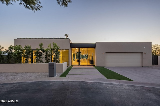 view of front facade featuring concrete driveway, an attached garage, and stucco siding