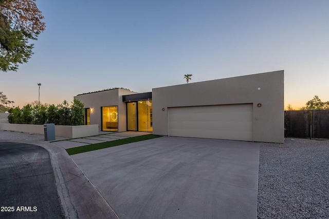 view of front of property featuring an attached garage, fence, concrete driveway, and stucco siding