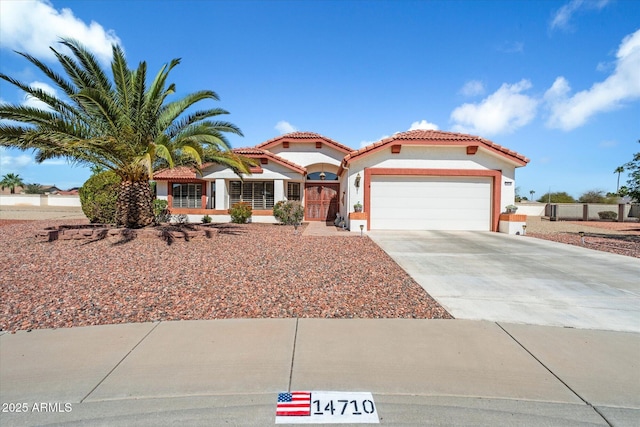 mediterranean / spanish house with concrete driveway, a tiled roof, an attached garage, and stucco siding