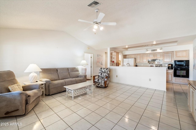 living room with a ceiling fan, visible vents, vaulted ceiling, and light tile patterned floors