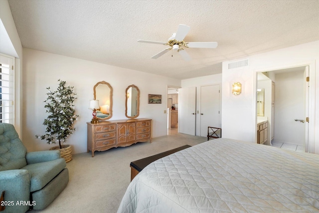 bedroom featuring a ceiling fan, visible vents, light carpet, and a textured ceiling