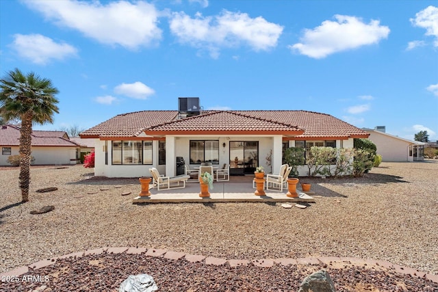 rear view of house featuring a patio area, a tile roof, central AC, and stucco siding