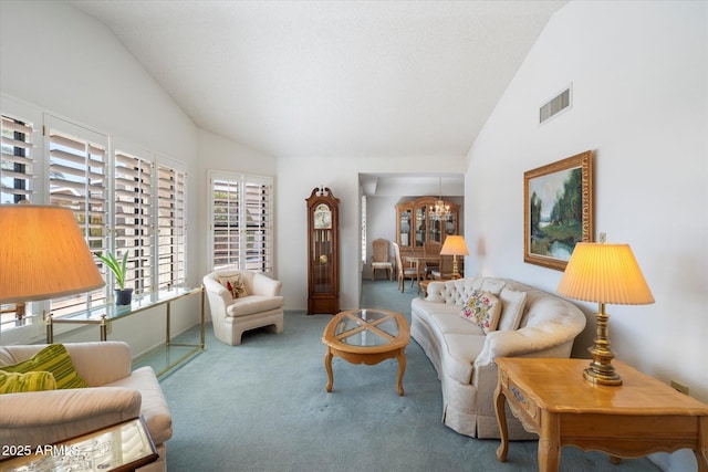 carpeted living area with high vaulted ceiling, visible vents, and a notable chandelier