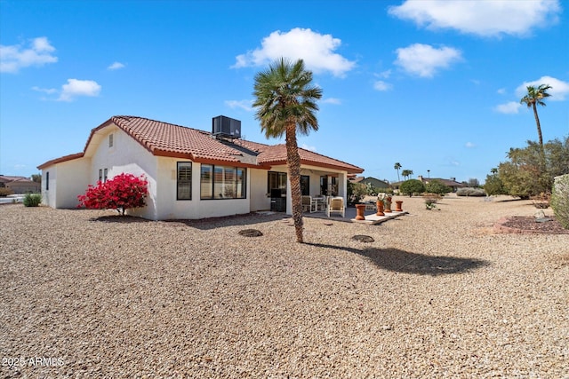 rear view of property featuring stucco siding, a patio, a tiled roof, and central air condition unit