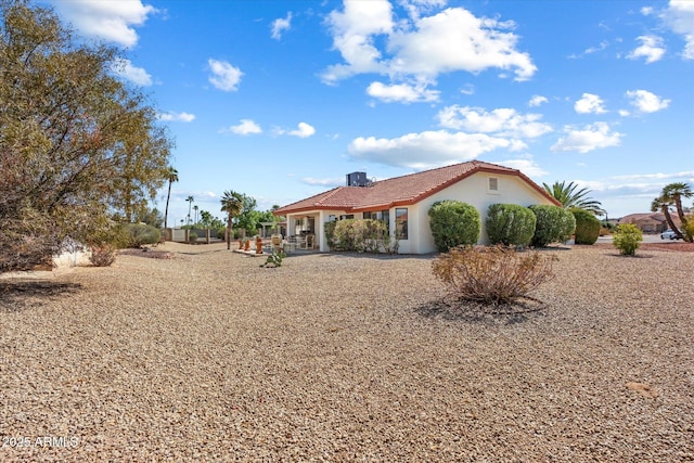 exterior space featuring a patio area, a tile roof, and stucco siding