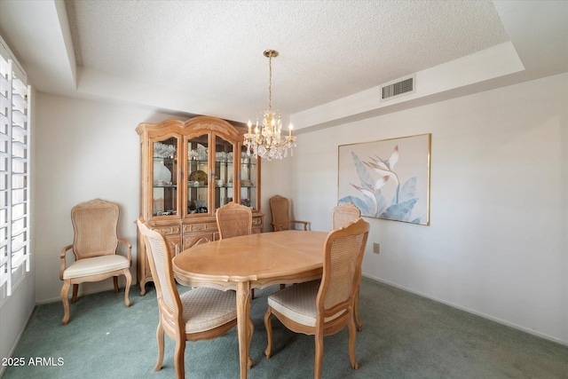 dining room with a textured ceiling, carpet flooring, visible vents, a raised ceiling, and an inviting chandelier