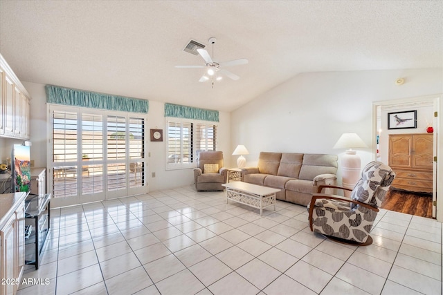 living room featuring visible vents, a ceiling fan, lofted ceiling, a textured ceiling, and light tile patterned flooring