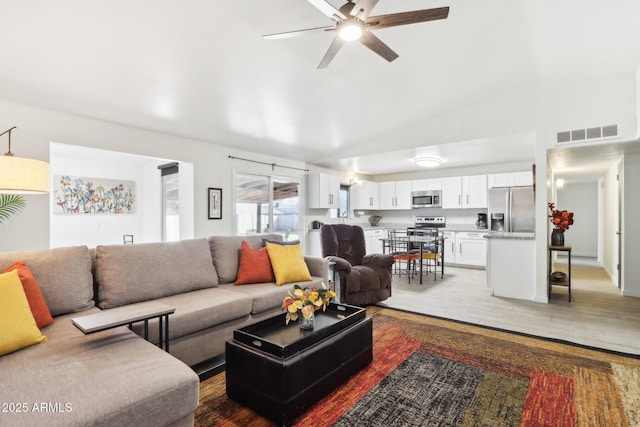 living room featuring ceiling fan, lofted ceiling, and light wood-type flooring