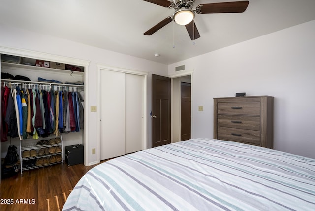 bedroom with dark wood-type flooring, two closets, and ceiling fan