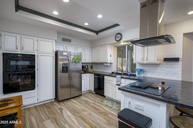 kitchen featuring white cabinetry, a raised ceiling, kitchen peninsula, island exhaust hood, and black appliances