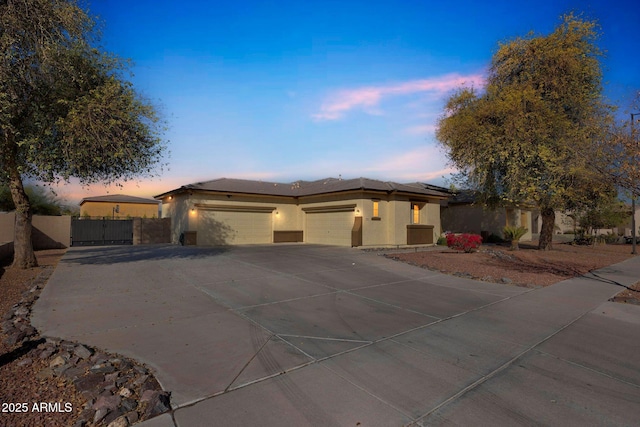 view of front facade featuring an attached garage, fence, concrete driveway, and stucco siding