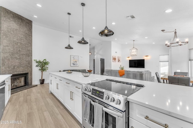 kitchen featuring pendant lighting, white cabinetry, light wood-type flooring, and appliances with stainless steel finishes