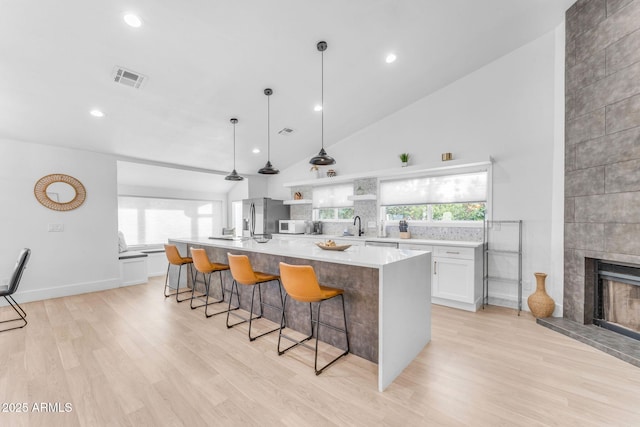 kitchen with pendant lighting, a breakfast bar area, white cabinetry, a spacious island, and stainless steel fridge with ice dispenser