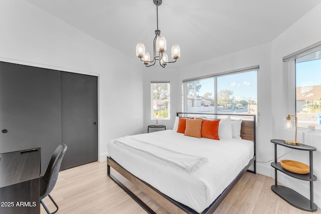 bedroom with vaulted ceiling, an inviting chandelier, and light wood-type flooring