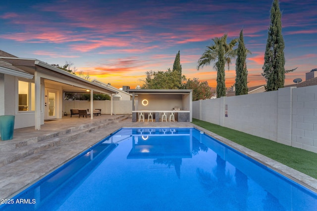 pool at dusk with a bar and a patio