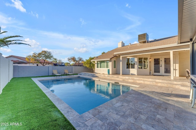 view of swimming pool featuring french doors, central AC, a patio area, and a lawn