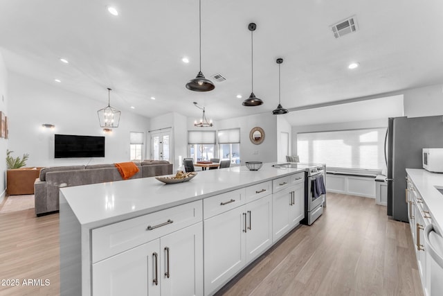 kitchen with white cabinetry, hanging light fixtures, stainless steel appliances, a center island, and light wood-type flooring