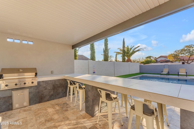 view of patio with a grill, an outdoor kitchen, a fenced in pool, and exterior bar