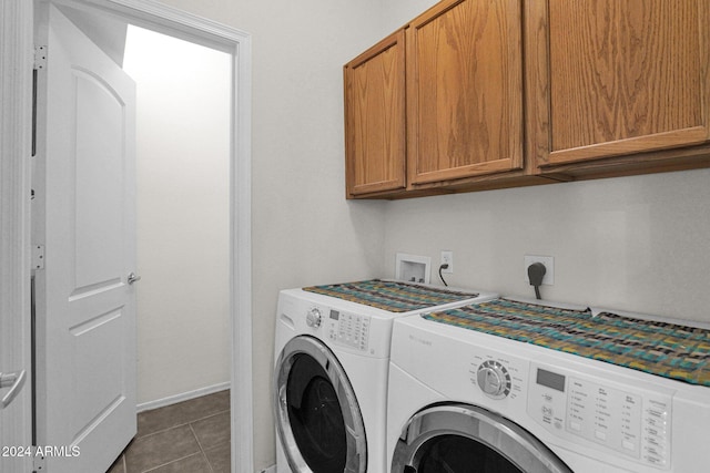 clothes washing area featuring cabinets, washer and dryer, and dark tile patterned flooring