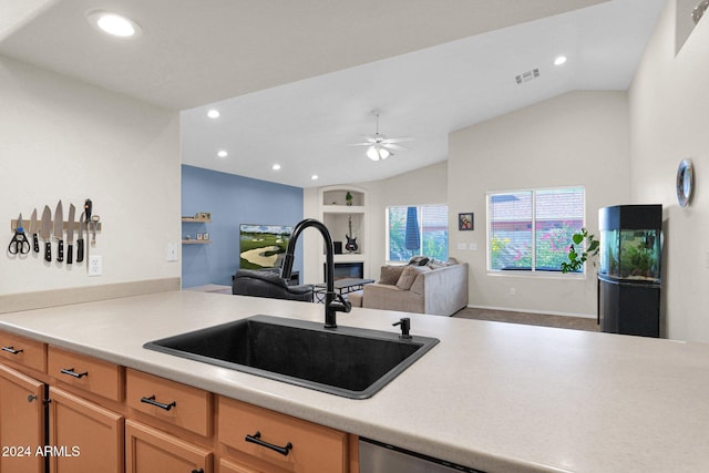 kitchen with kitchen peninsula, built in shelves, vaulted ceiling, ceiling fan, and sink