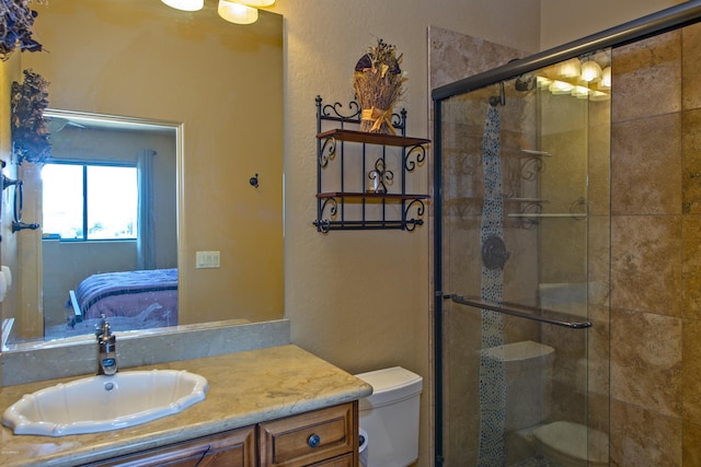 bathroom featuring vanity, toilet, and a shower with door