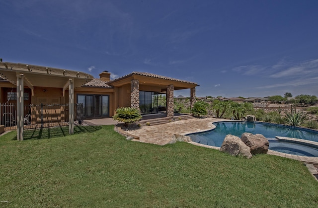 rear view of property featuring a lawn, a pool with hot tub, and a patio area