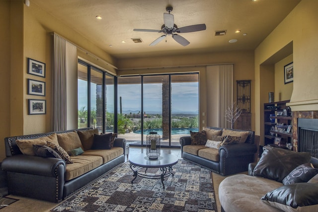 living room with ceiling fan and a fireplace