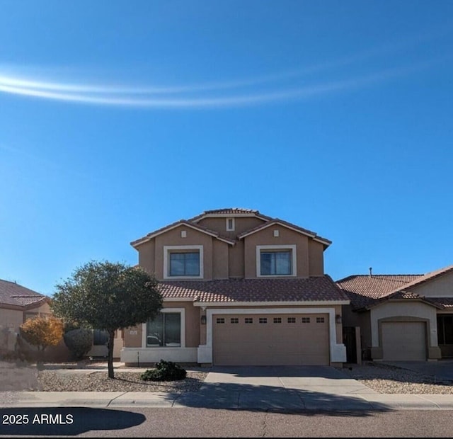 view of front of home featuring an attached garage, a tiled roof, concrete driveway, and stucco siding