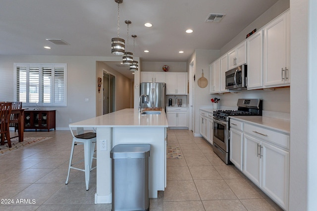 kitchen featuring appliances with stainless steel finishes, white cabinets, and an island with sink