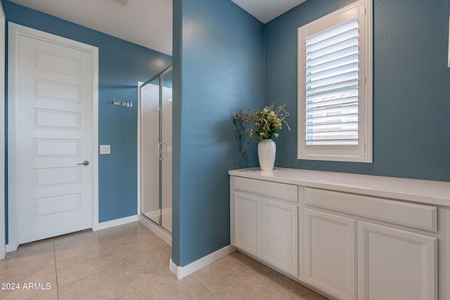 bathroom with tile patterned flooring, an enclosed shower, and a wealth of natural light