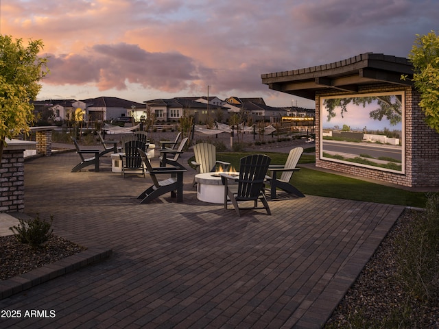 patio terrace at dusk featuring a fire pit and a lawn