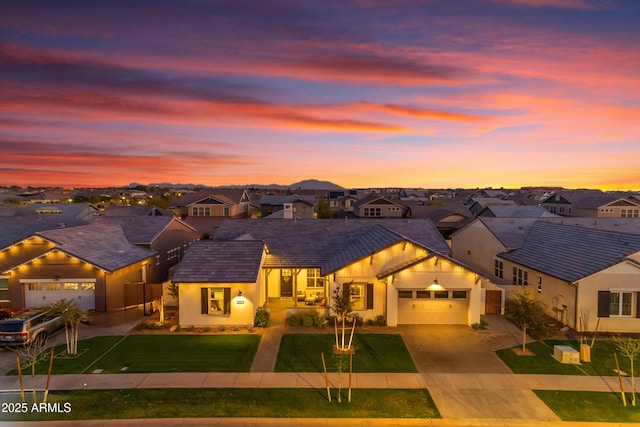 view of front of property featuring stucco siding, a lawn, driveway, a residential view, and an attached garage