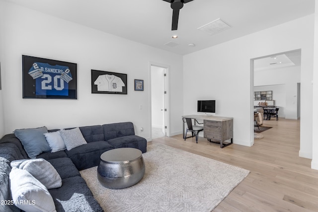 living area with baseboards, light wood-style floors, and a ceiling fan