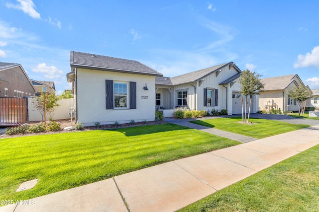 view of front of house with a front yard, an attached garage, fence, and a tile roof