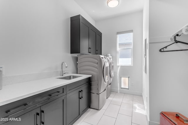 laundry room featuring a sink, cabinet space, separate washer and dryer, light tile patterned floors, and baseboards