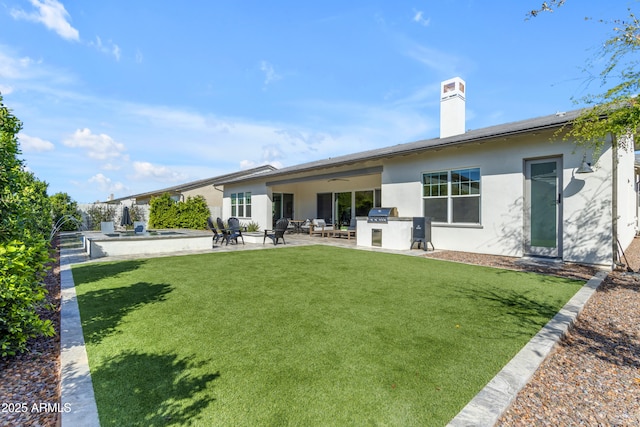 rear view of property with ceiling fan, stucco siding, a lawn, a patio area, and area for grilling